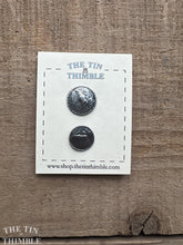 Load image into Gallery viewer, Pair of silver Scandinavian buttons on a 'The Tin Thimble' branded card against a wooden background.